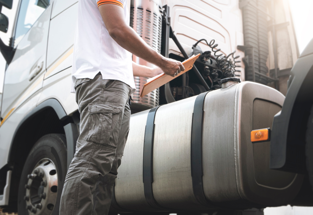 Truck,Driver,Holding,Clipboard,Is,Checking,Semi,Truck,Fuel,Tank.